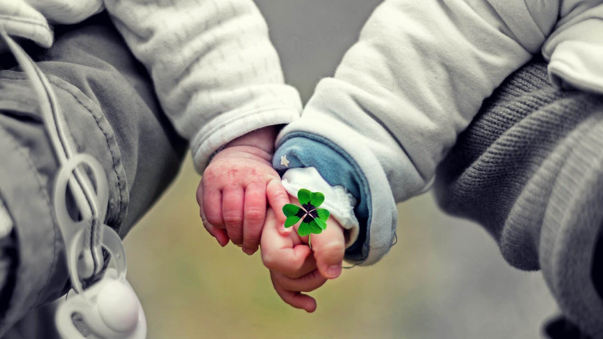 Babys halten Händchen und Kleeblatt