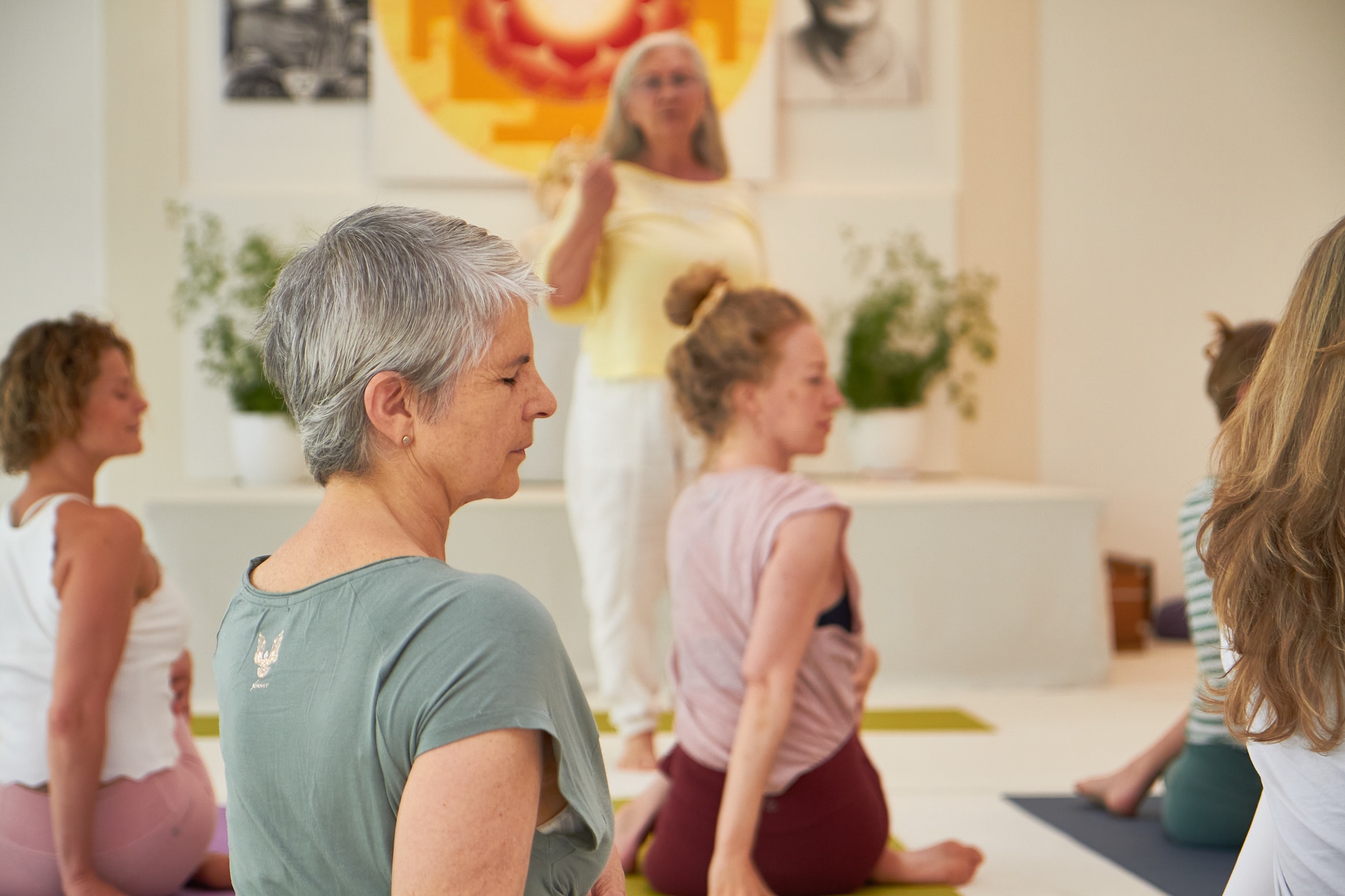 Yogaschülerinnen in einer ruhigen Unterrichtsstunde im Yoga Vidya Ashram, angeleitet von einer Yogalehrerin, während sie ihre passende Yoga Ausbildung finden möchten.