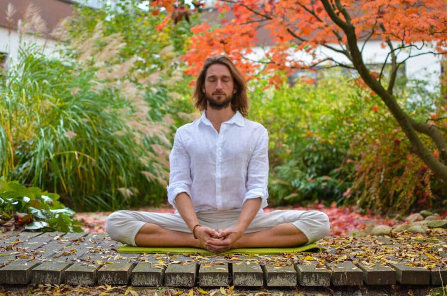 Mann sitzt in ruhiger Schmetterlingshaltung im herbstlichen Garten – Yoga für die Faszien zur Verbesserung von Beweglichkeit und Entspannung
