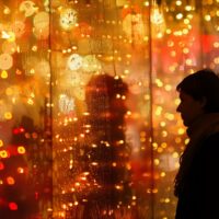 Silhouette einer Person vor warmen, goldenen Weihnachtslichtern und Reflexionen – stimmungsvolle Adventsszene für innere Ruhe und Entschleunigung.