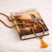 Geschlossene Bhagavad Gita mit Mala aus Holzperlen auf hellem Hintergrund