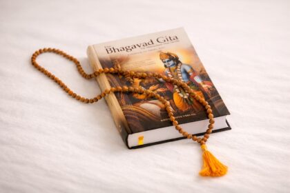 Geschlossene Bhagavad Gita mit Mala aus Holzperlen auf hellem Hintergrund