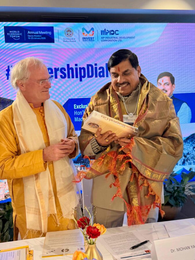Dr. Mohan Yadav betrachtet die Bhagavad Gita von Sukadev Bretz beim Treffen von Yoga Vidya in Davos