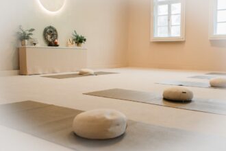 Heller Meditationsraum mit Yogamatten, Meditationskissen, Altar und Fenster mit Tageslicht