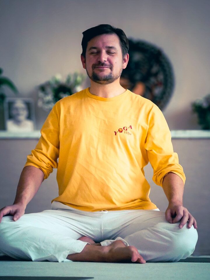 Person sitzt in aufrechter Haltung in Meditation auf einer Yogamatte