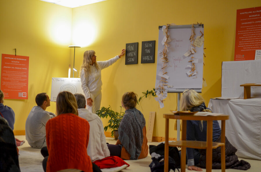 Glücks AG Ausbildung: Devani Christine Stibi erklärt Konzepte im Stehen. Teilnehmende sitzen im Seminarraum und hören zu.
