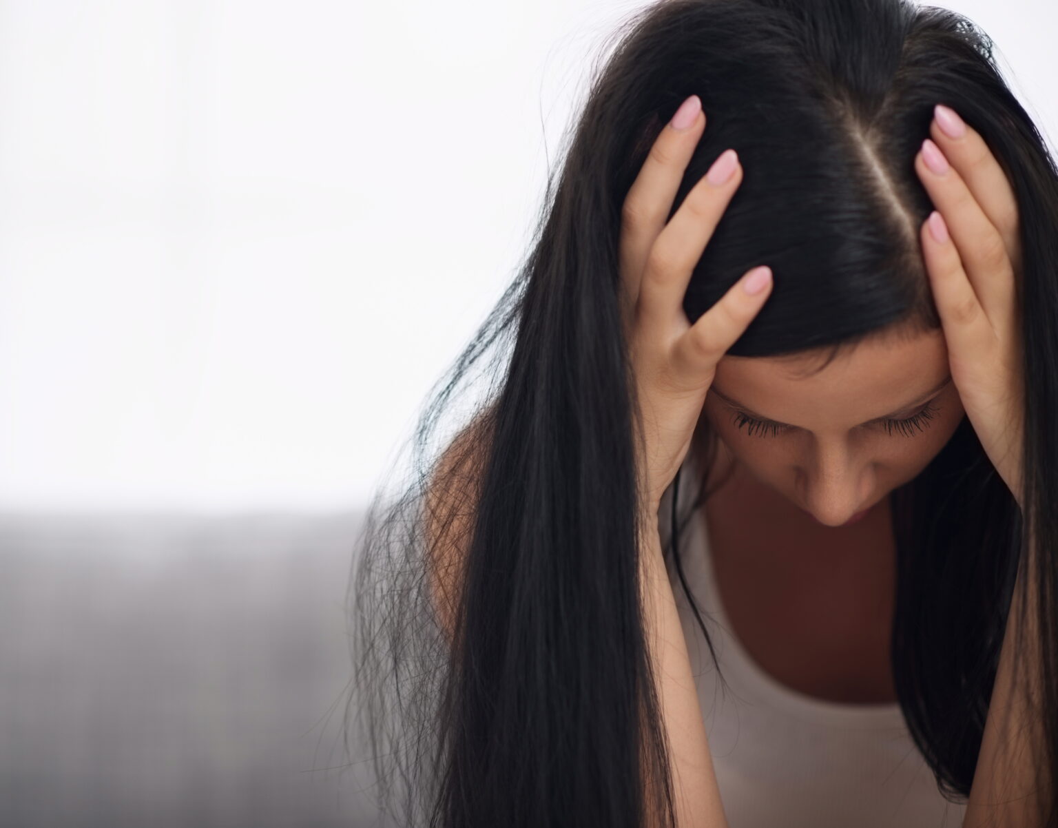 Frau mit gesenktem Blick und Händen am Kopf als Symbol für psychische Belastung, innere Unruhe und depressive Verstimmung