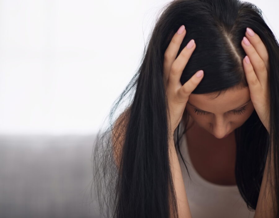 Frau mit gesenktem Blick und Händen am Kopf als Symbol für psychische Belastung, innere Unruhe und depressive Verstimmung