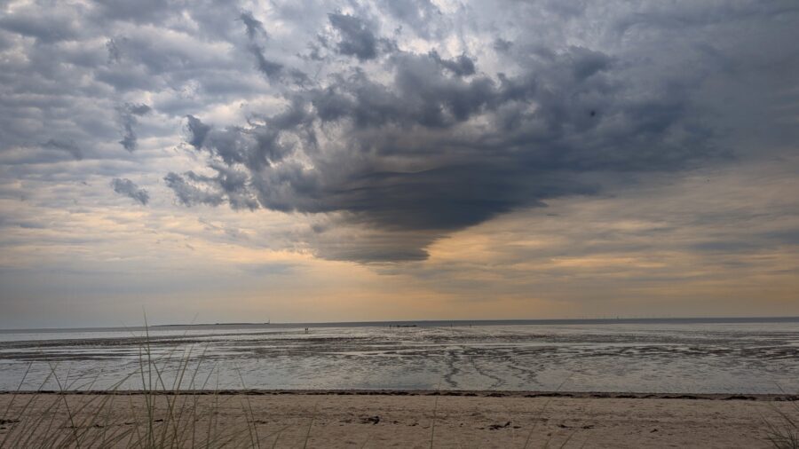 Dunkle Wolkenformation über dem Wattenmeer an der Nordsee mit weiter Horizontlinie.