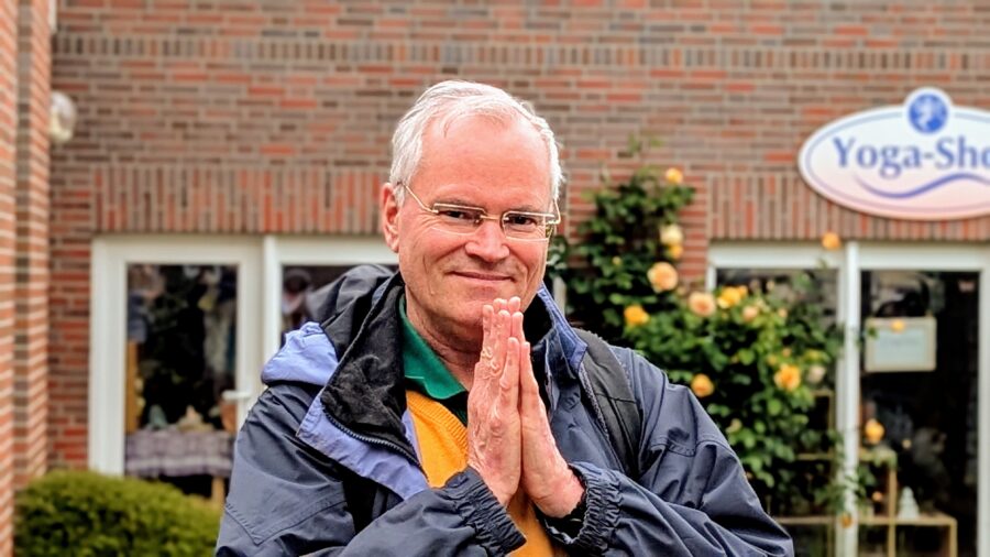 Sukadev in blauer Regenjacke in Namaste vorm Nordsee-Ashram
