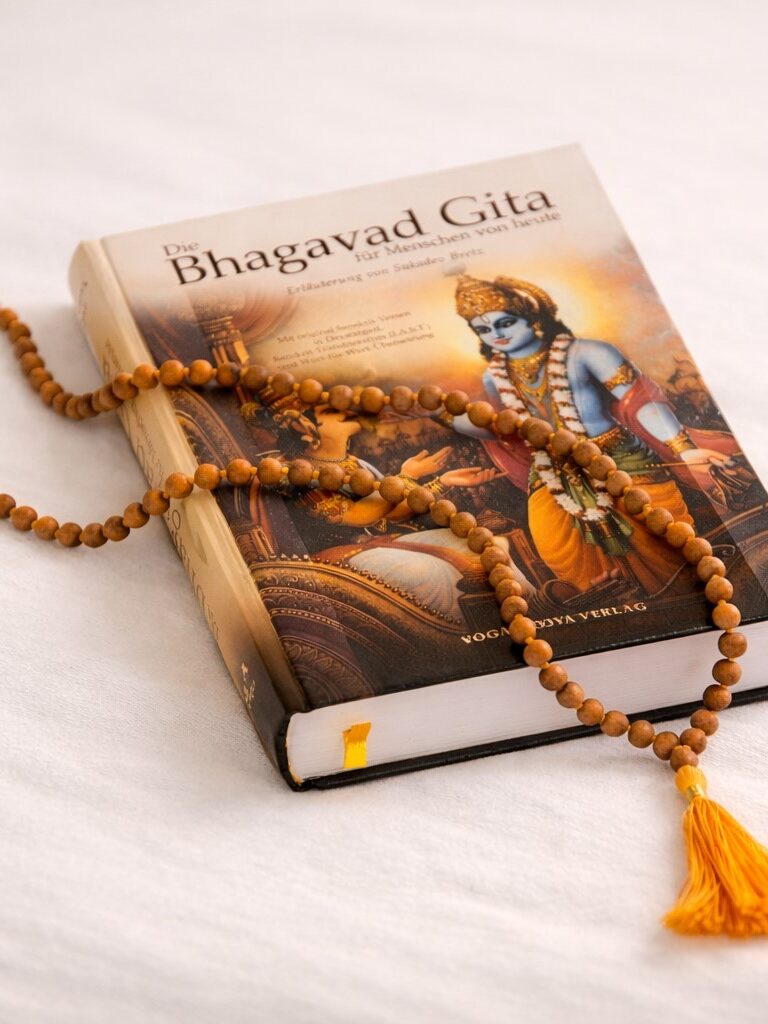 Geschlossene Bhagavad Gita mit Mala aus Holzperlen auf hellem Hintergrund
