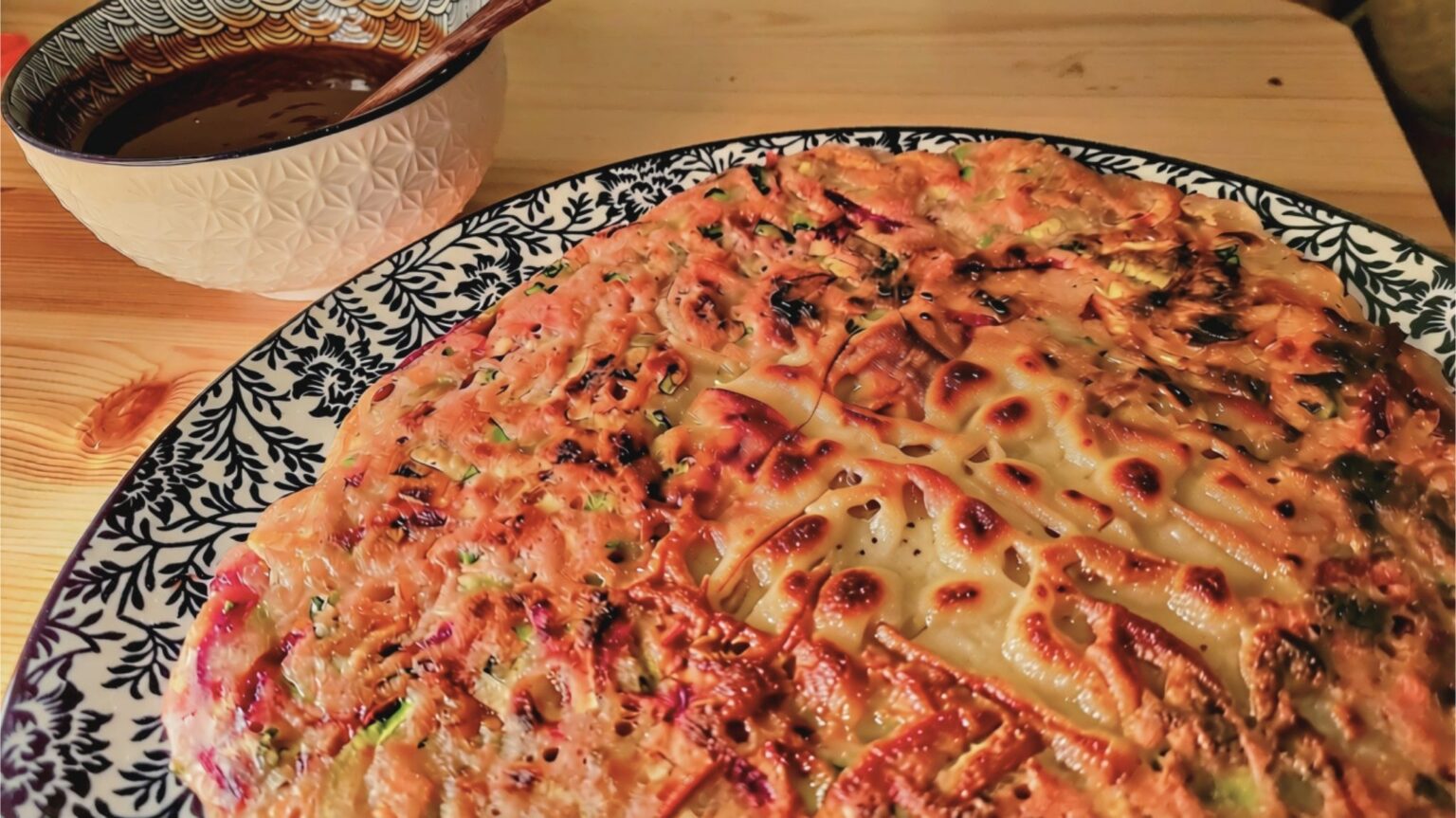 Fertiger koreanischer Gemüsepfannkuchen (Yachaejeon) auf blau-weißem Teller