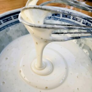 Fließfähiger Pfannkuchenteig am Schneebesen in Schüssel