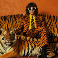 Mann im Tigeranzug auf Tigerrsofa mit Tiger