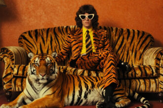 Mann im Tigeranzug auf Tigerrsofa mit Tiger