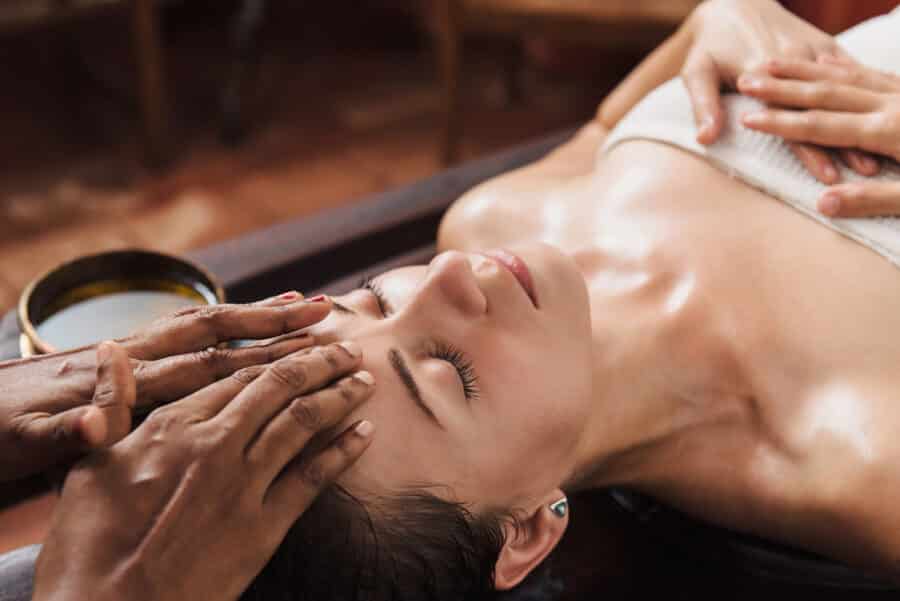 Ayurvedic face massage with oil on the wooden table - Marma Massage